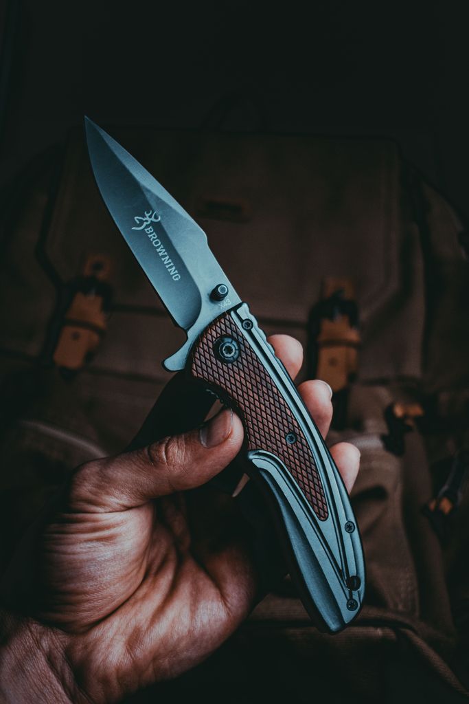 A detailed close-up view of a hand holding a sharp tactical knife, depicting precision and craftsmanship.