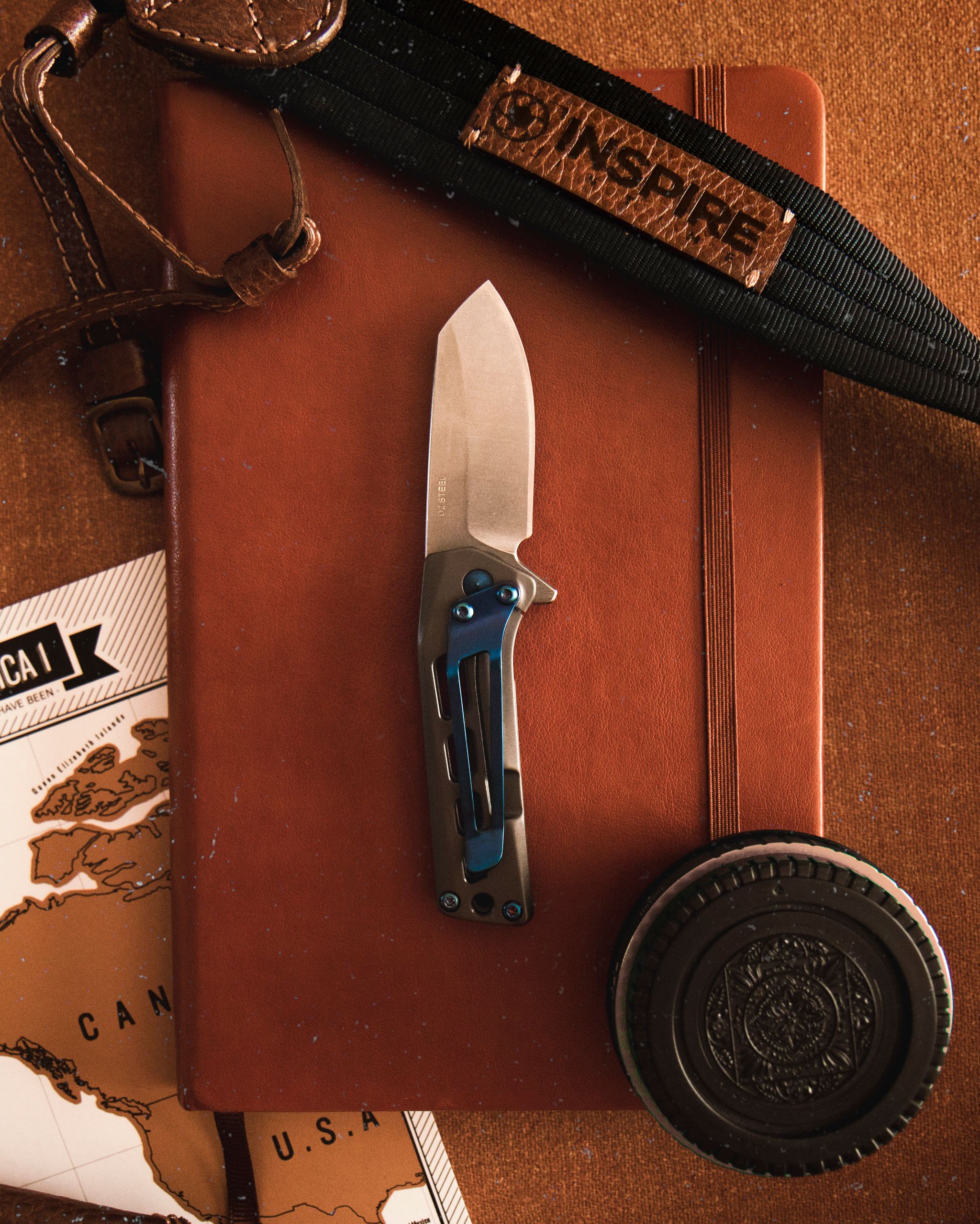 Flat lay of a vintage knife on a leather journal with travel gear for adventure seekers.